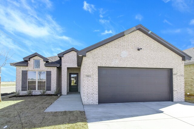 view of front of property featuring a garage, driveway, and brick siding