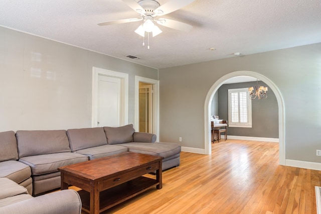 living room with a textured ceiling, light hardwood / wood-style flooring, and ceiling fan