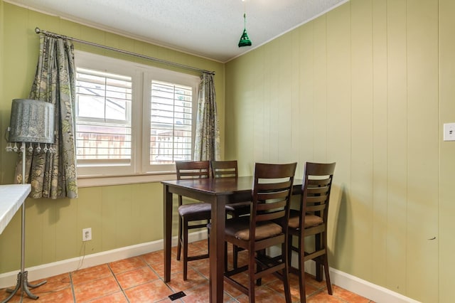 dining space featuring light tile patterned floors, ornamental molding, and a textured ceiling