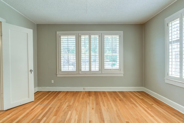 spare room with light hardwood / wood-style floors and a textured ceiling