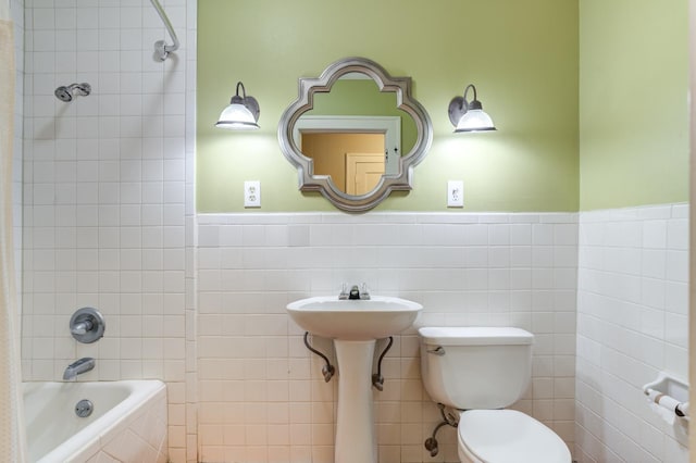 bathroom with tile walls, tiled shower / bath combo, and toilet