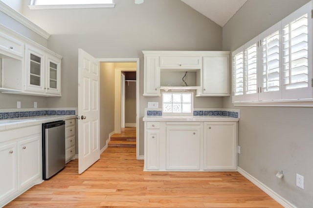 kitchen with white cabinets, vaulted ceiling, light hardwood / wood-style floors, and dishwasher