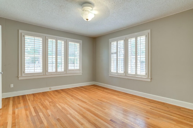 unfurnished room with light hardwood / wood-style floors, a textured ceiling, and a wealth of natural light