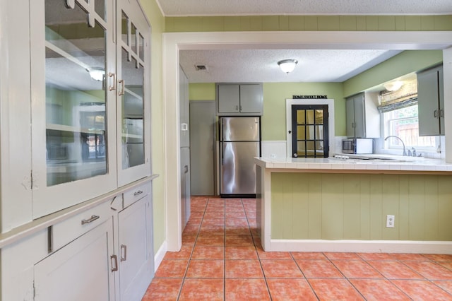 kitchen featuring stainless steel fridge, tile countertops, a textured ceiling, and light tile patterned floors