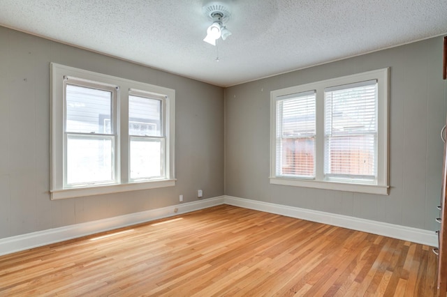 unfurnished room with ceiling fan, a textured ceiling, and light wood-type flooring