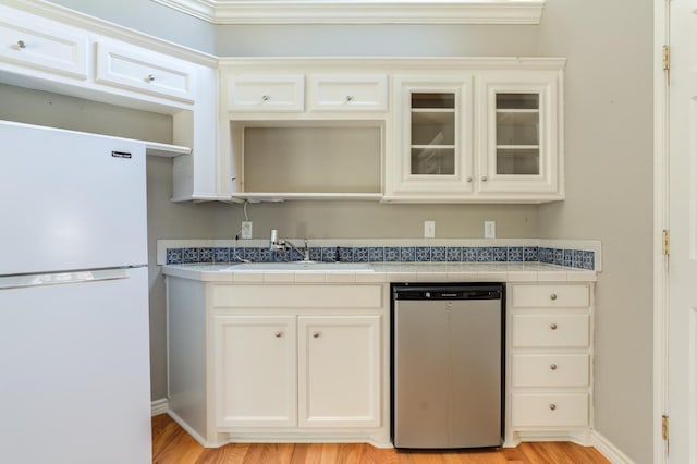 kitchen featuring white refrigerator, stainless steel dishwasher, tile counters, and sink