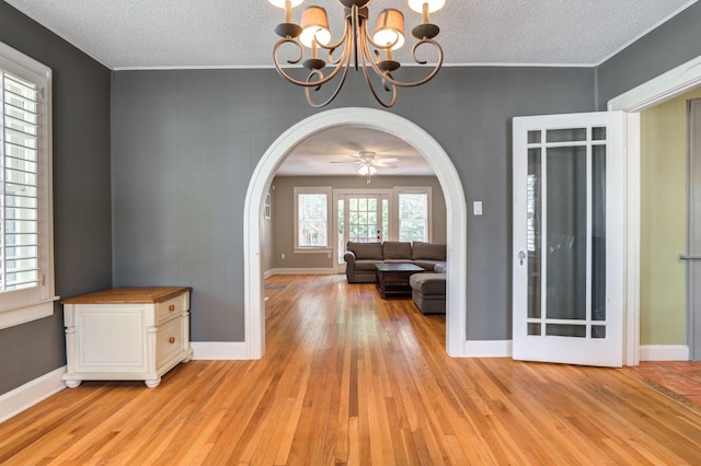 interior space with ceiling fan with notable chandelier, a textured ceiling, and light wood-type flooring