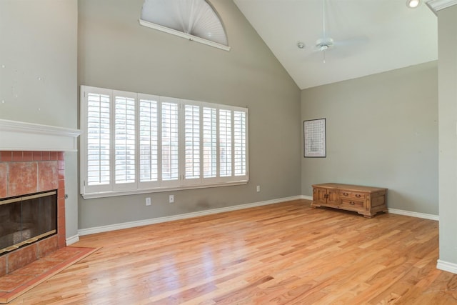 unfurnished living room with ceiling fan, high vaulted ceiling, a fireplace, and light hardwood / wood-style floors