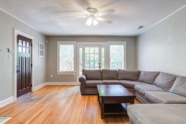 living room with crown molding, ceiling fan, a textured ceiling, and light wood-type flooring