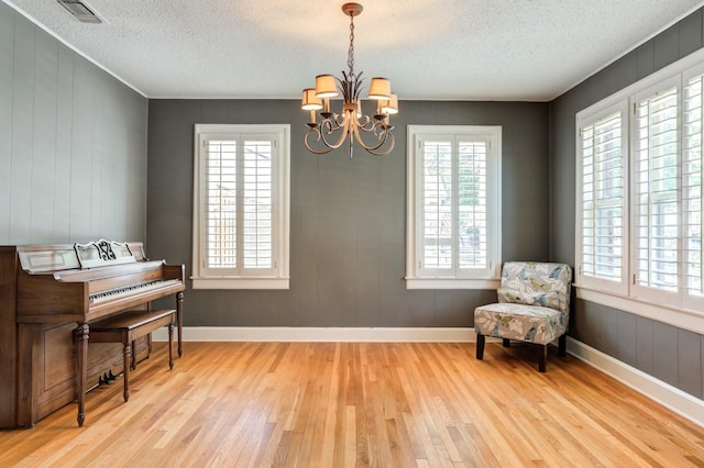 sitting room featuring a chandelier, a textured ceiling, and light wood-type flooring