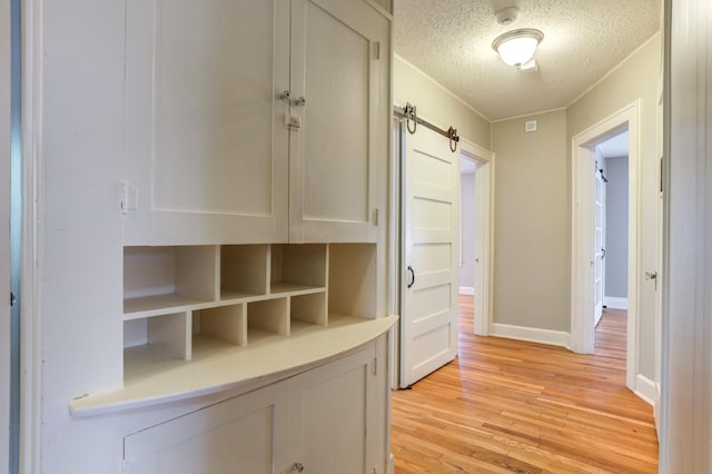 interior space featuring a barn door, a textured ceiling, and light hardwood / wood-style floors