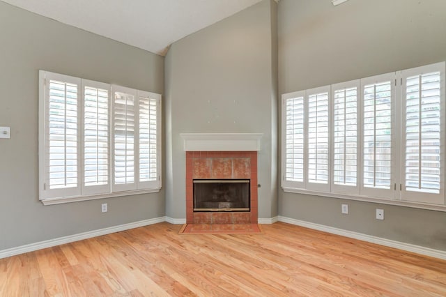 unfurnished living room featuring vaulted ceiling, a healthy amount of sunlight, a fireplace, and light hardwood / wood-style floors