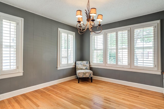 living area featuring hardwood / wood-style floors, a textured ceiling, and a chandelier