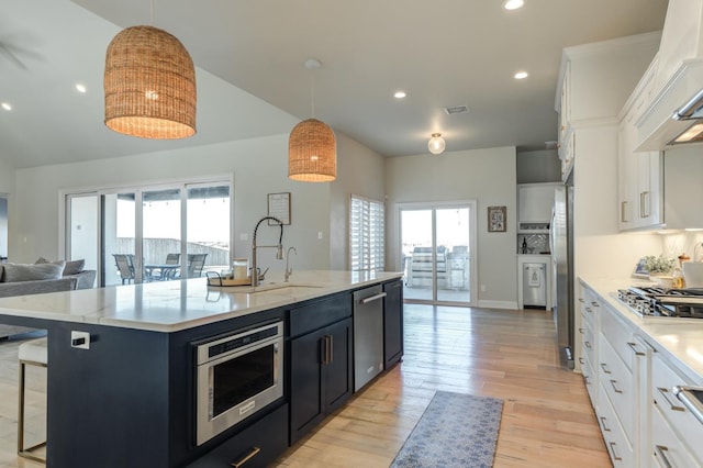 kitchen featuring a kitchen island with sink, white cabinets, and decorative light fixtures