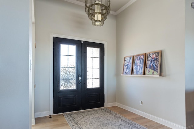 entryway featuring crown molding, light hardwood / wood-style flooring, french doors, and a chandelier