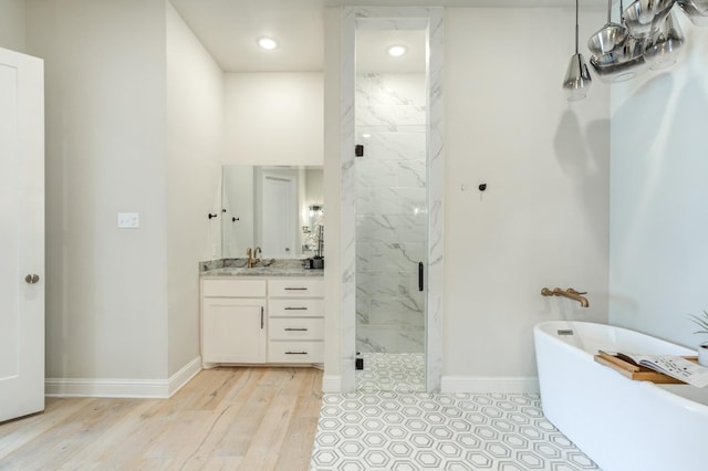 bathroom featuring hardwood / wood-style flooring, plus walk in shower, and vanity