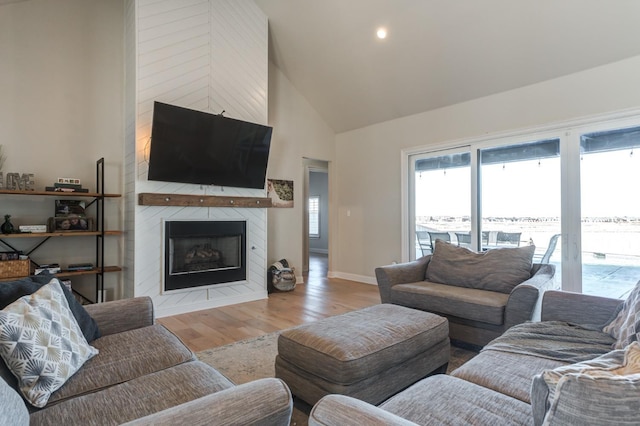 living room with light hardwood / wood-style flooring, high vaulted ceiling, and a large fireplace