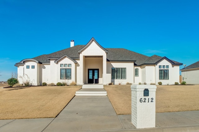 french provincial home with a front yard