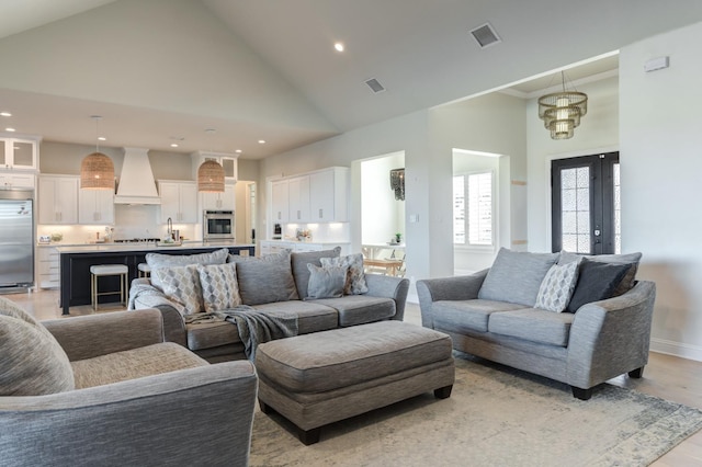 living room featuring sink, light hardwood / wood-style flooring, high vaulted ceiling, and french doors