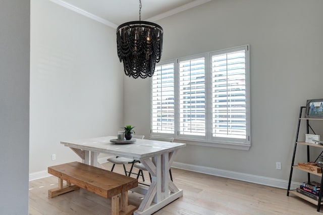 dining room featuring ornamental molding, light wood-type flooring, and an inviting chandelier