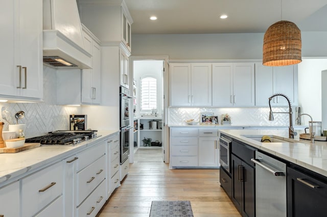 kitchen featuring premium range hood, sink, pendant lighting, stainless steel appliances, and white cabinets