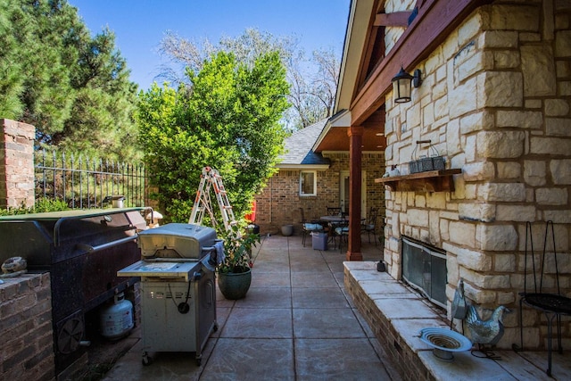 view of patio / terrace with area for grilling, an outdoor stone fireplace, and an outdoor kitchen