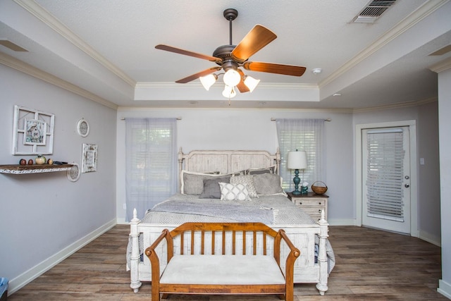 bedroom featuring ornamental molding, dark hardwood / wood-style floors, ceiling fan, and a tray ceiling