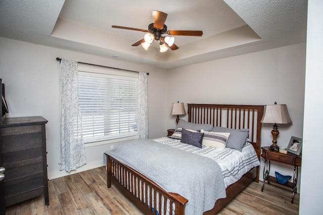 bedroom featuring a raised ceiling, hardwood / wood-style flooring, and ceiling fan