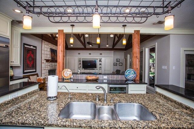 kitchen with decorative light fixtures, sink, a stone fireplace, and dark stone countertops