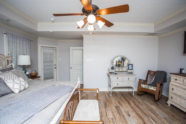 bedroom with light wood-type flooring, ornamental molding, a tray ceiling, a closet, and ceiling fan