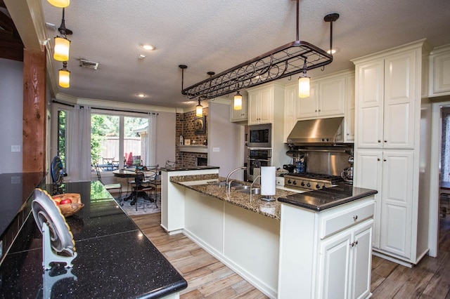 kitchen with white cabinetry, an island with sink, and stainless steel oven