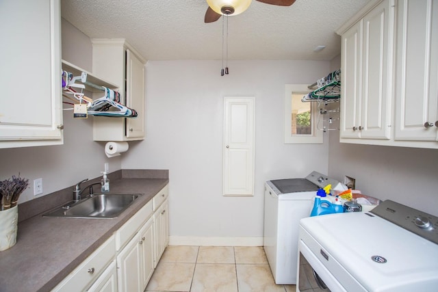 laundry room with light tile patterned flooring, sink, cabinets, separate washer and dryer, and a textured ceiling