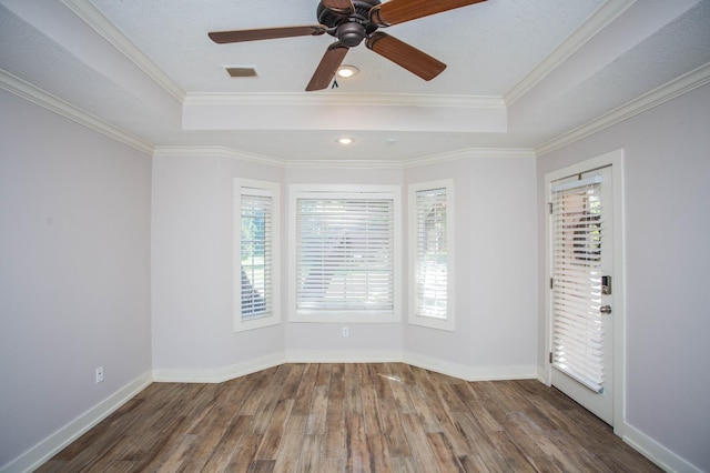 spare room with dark wood-type flooring, ornamental molding, and a raised ceiling