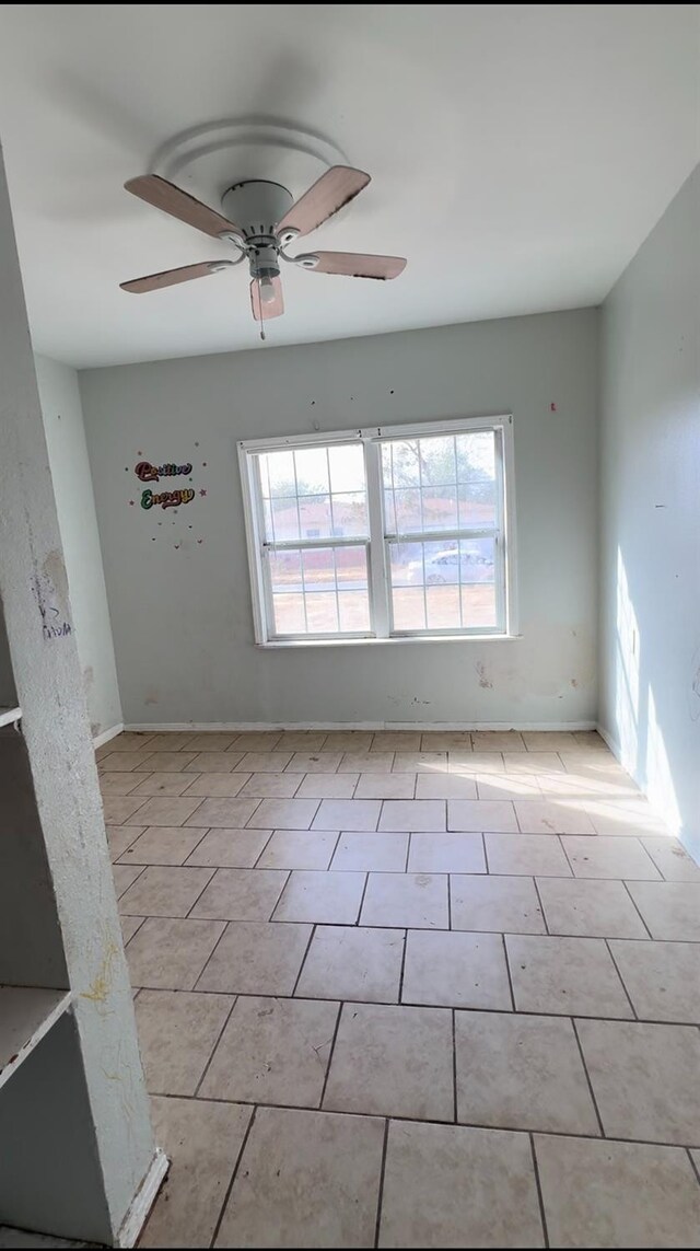 tiled empty room featuring ceiling fan