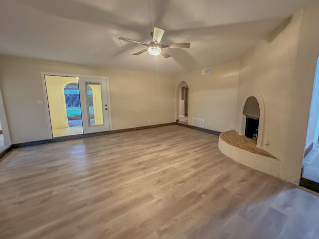 unfurnished living room with a fireplace, ceiling fan, and light wood-type flooring