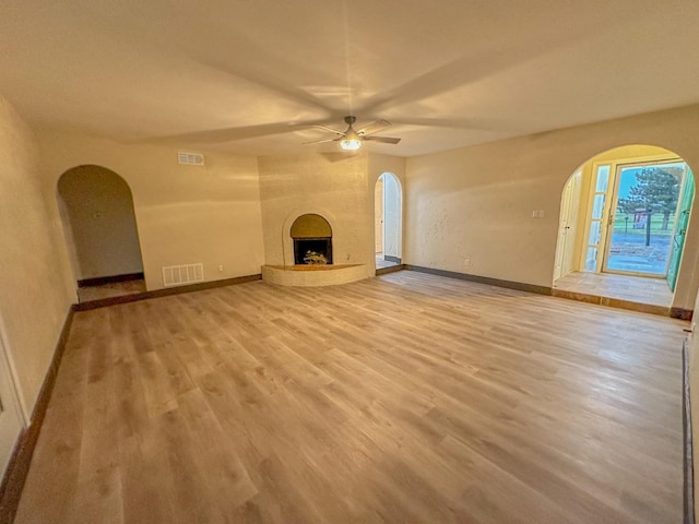 unfurnished living room featuring hardwood / wood-style flooring, ceiling fan, and a fireplace