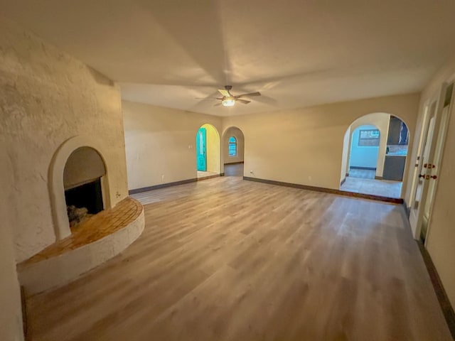 unfurnished living room featuring ceiling fan, a large fireplace, and light hardwood / wood-style floors