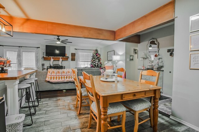 dining space featuring ceiling fan, wood-type flooring, and beamed ceiling