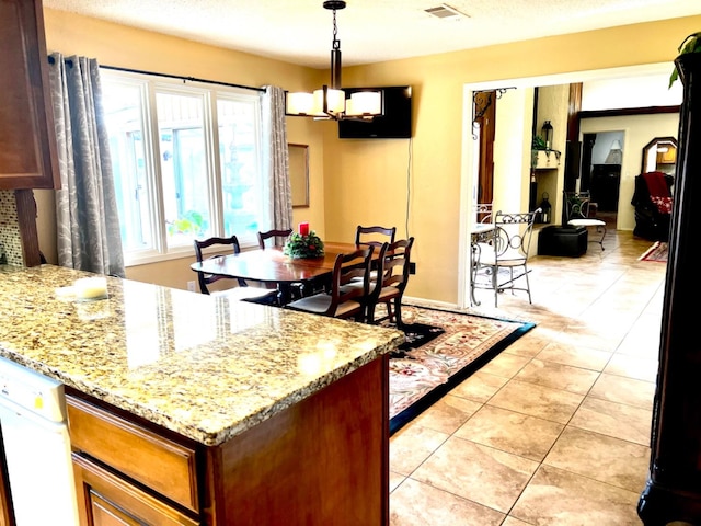 kitchen featuring light stone counters, a chandelier, hanging light fixtures, and light tile patterned floors