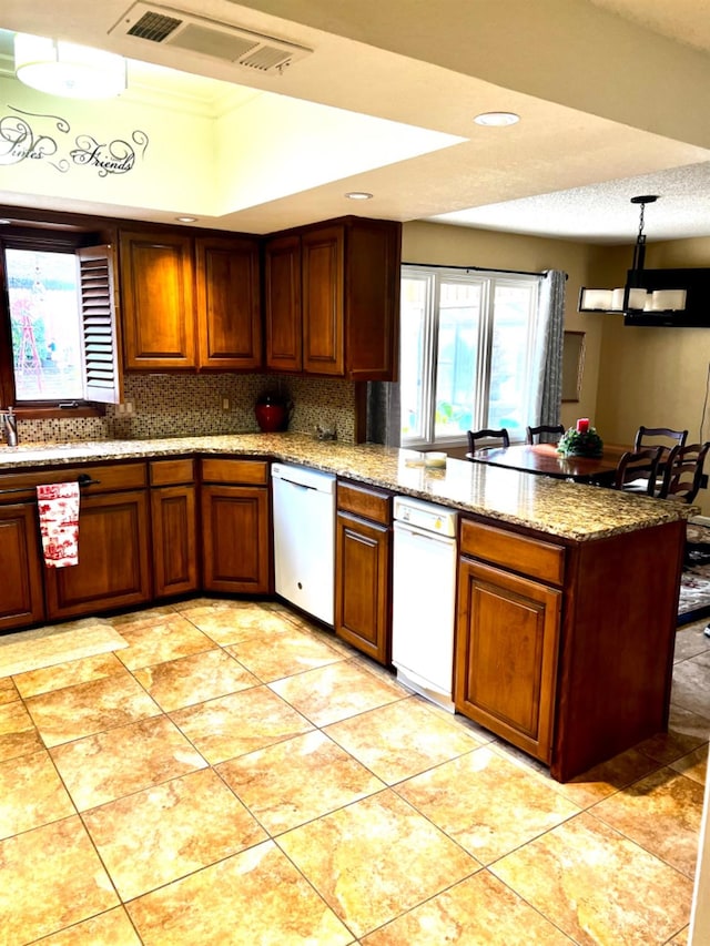 kitchen featuring tasteful backsplash, dishwasher, pendant lighting, and kitchen peninsula