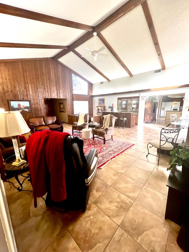 tiled living room with vaulted ceiling with beams, wooden walls, and ceiling fan