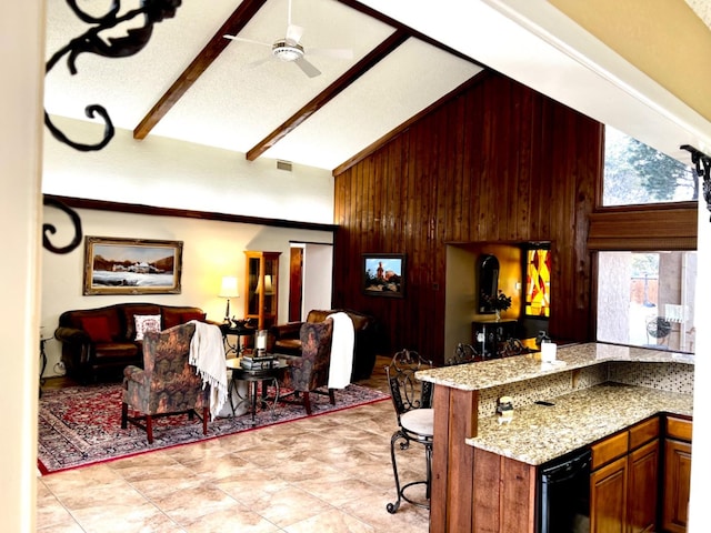 kitchen with high vaulted ceiling, wooden walls, kitchen peninsula, light stone countertops, and beam ceiling