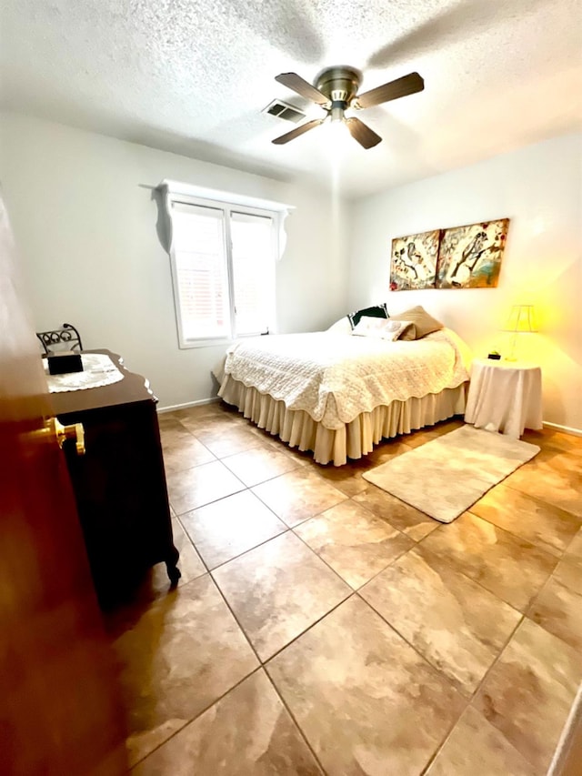 bedroom with light tile patterned flooring, ceiling fan, and a textured ceiling