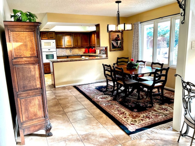 dining space featuring light tile patterned flooring and a textured ceiling