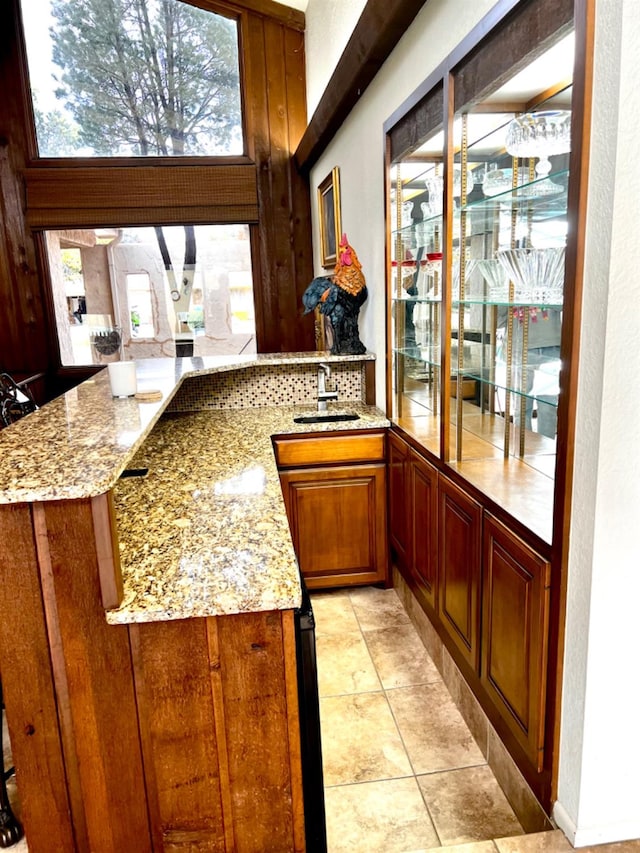 bar with light stone countertops, sink, and light tile patterned floors