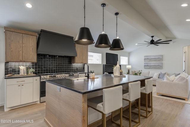 3617 127th St, Lubbock, TX 79423 - kitchen with custom range hood, stainless steel gas stove, light wood-type flooring, decorative backsplash, and an island with sink