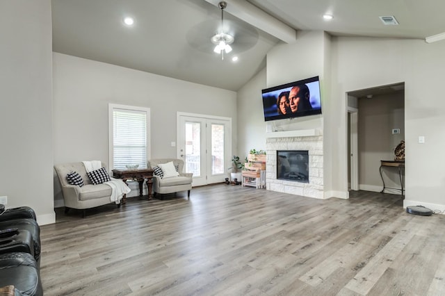 living room with a stone fireplace, high vaulted ceiling, beamed ceiling, ceiling fan, and light hardwood / wood-style floors