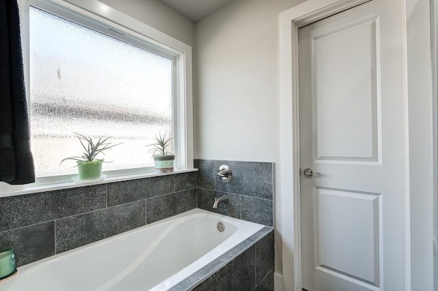 bathroom featuring a healthy amount of sunlight and tiled tub