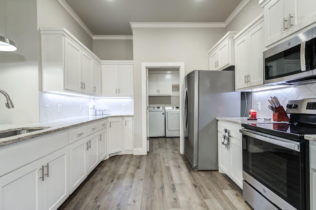 kitchen with sink, stainless steel appliances, light stone countertops, white cabinets, and washing machine and clothes dryer