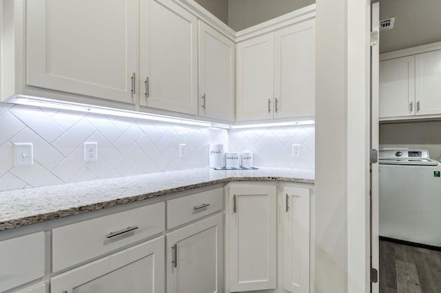 kitchen with washer / clothes dryer, white cabinets, and light stone counters